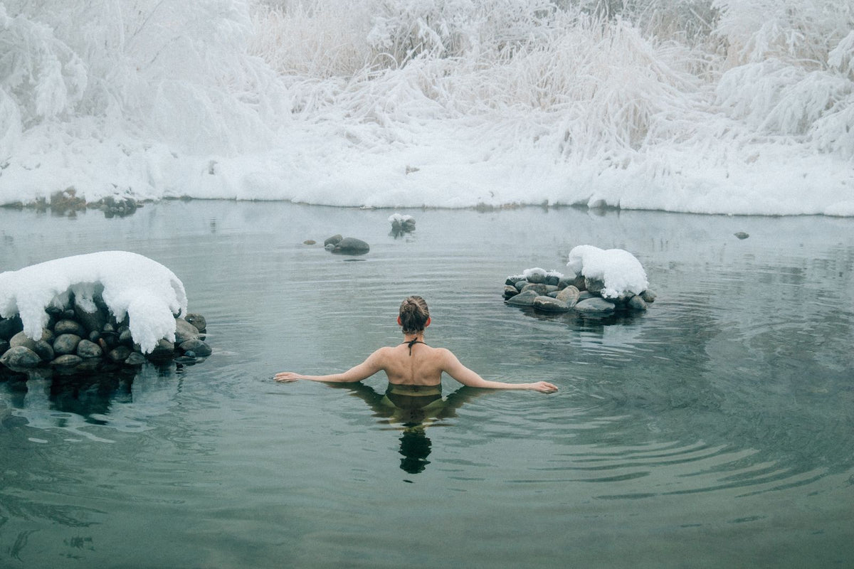 Mujer bañándose en agua fría rodeada de nieve