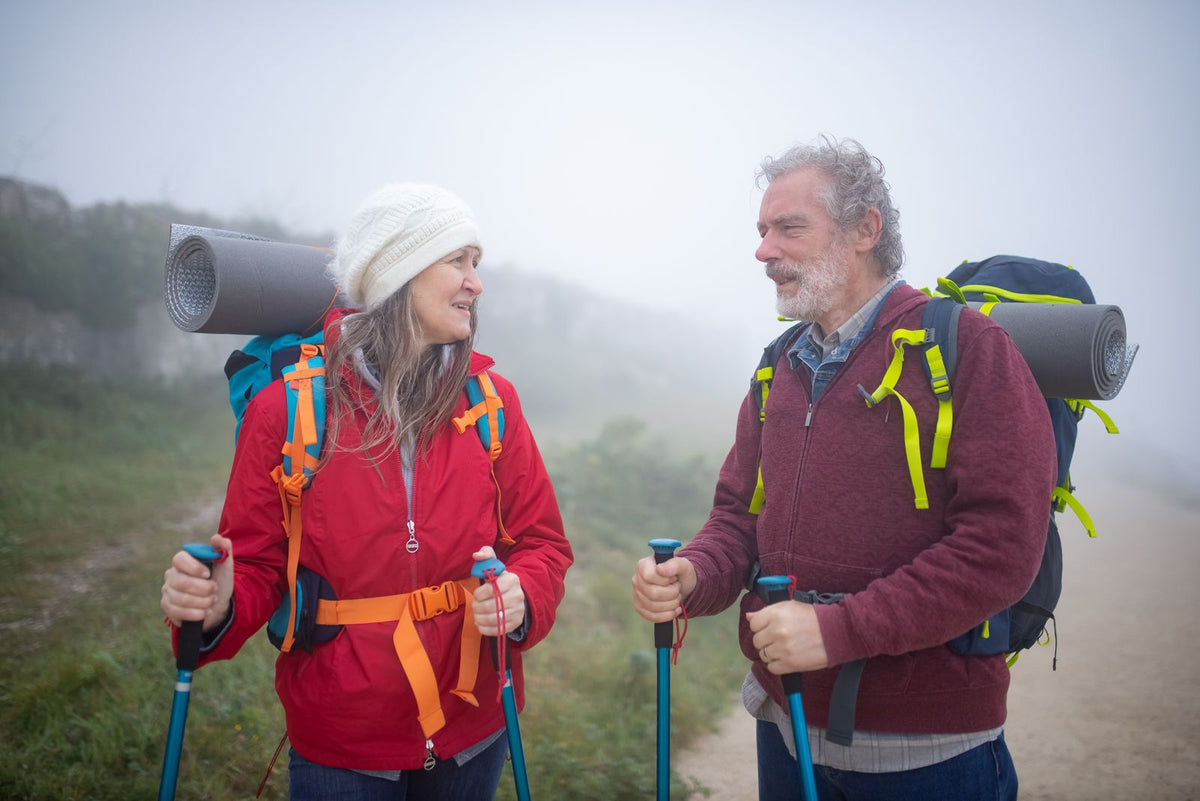 Pareja mayor de excursión con mochilas y bastones
