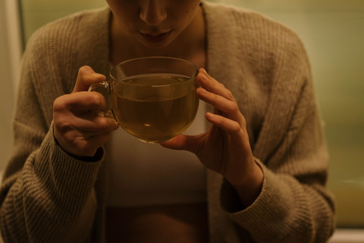 Mujer con una infusión caliente entre las manos por la tarde